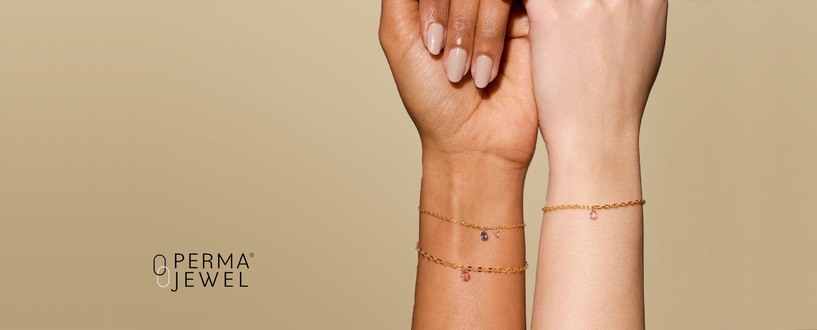 Two wrists side by side wearing slim gold Perma-jewel chains with small coloured stone drops.